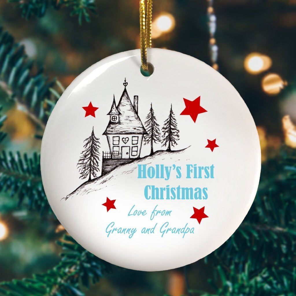 A round ceramic Christmas decoration with an illustration of a house and the words "Holly's First Christmas love Granny and Grandpa" 