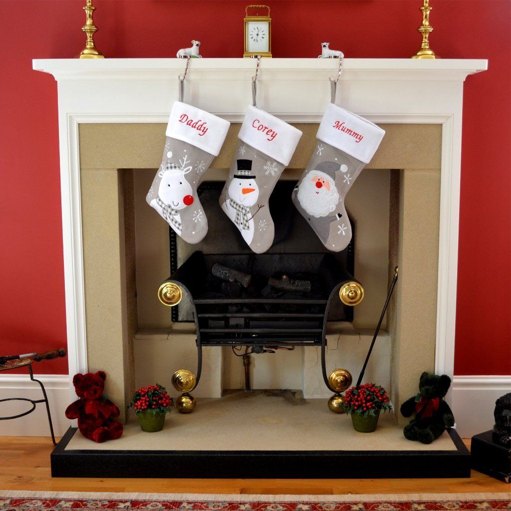 3 personalised Christmas stockings hanging on a fire place 